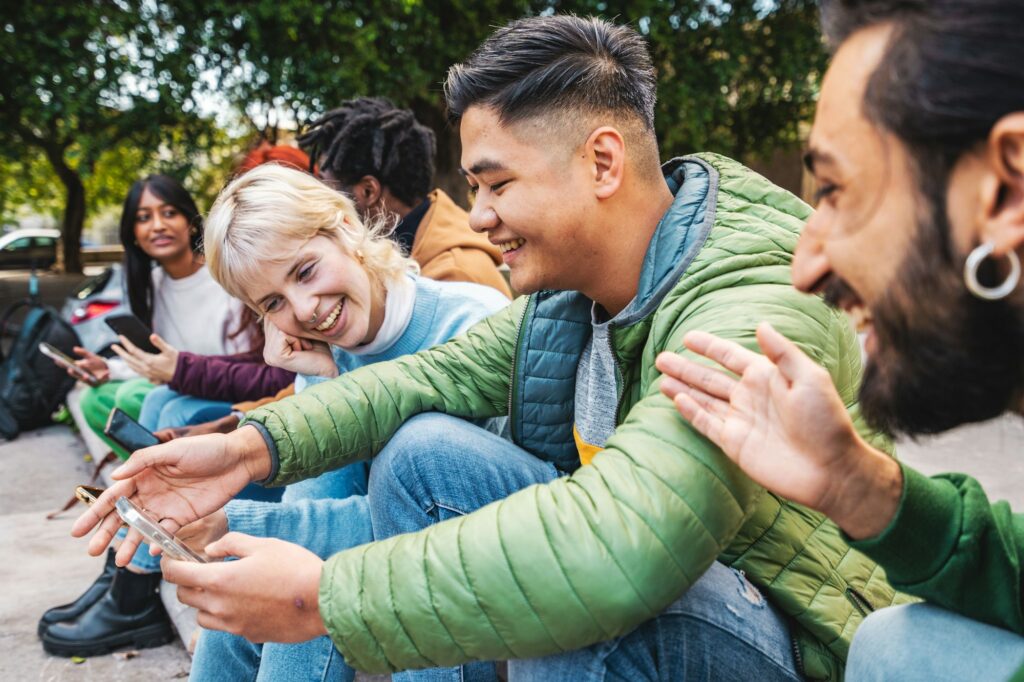 Diverse Gen Z Friends Sharing Content on Smartphone Outdoors